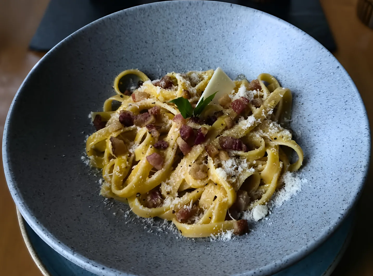 Pappardelle a la carbonara con guanciale y queso rallado en un plato hondo gris