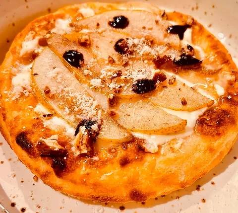 Pizza frita de cuatro quesos con láminas de pera y nuez, vista desde arriba